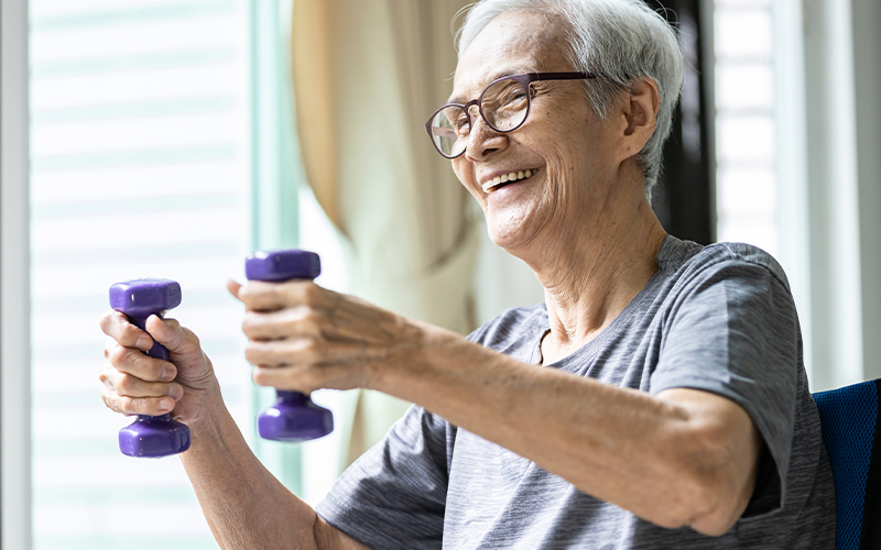 An elderly man lifting small weights