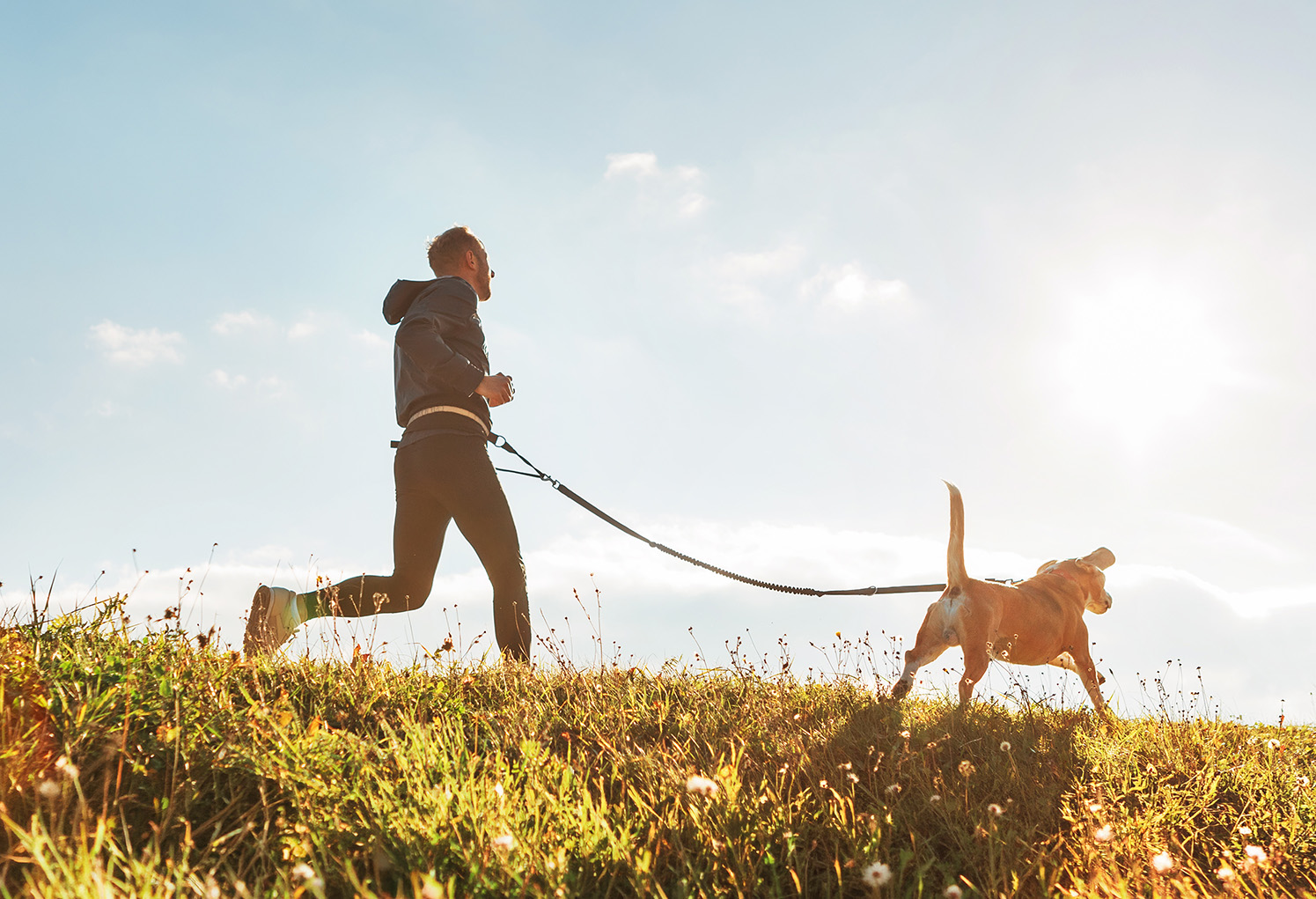 A man running through a field with a dog